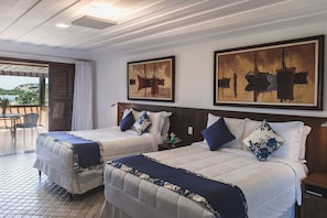 A hotel room with two beds, a balcony, and artwork on the walls.