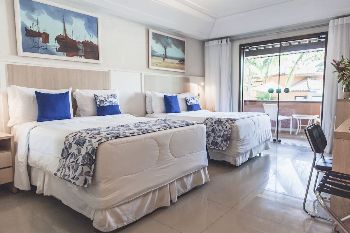 Une chambre d’hôtel avec deux lits, un bureau et une vue sur l’extérieur.