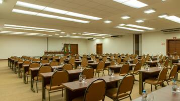 A conference room with rows of tables and chairs, equipped with water bottles and glasses.