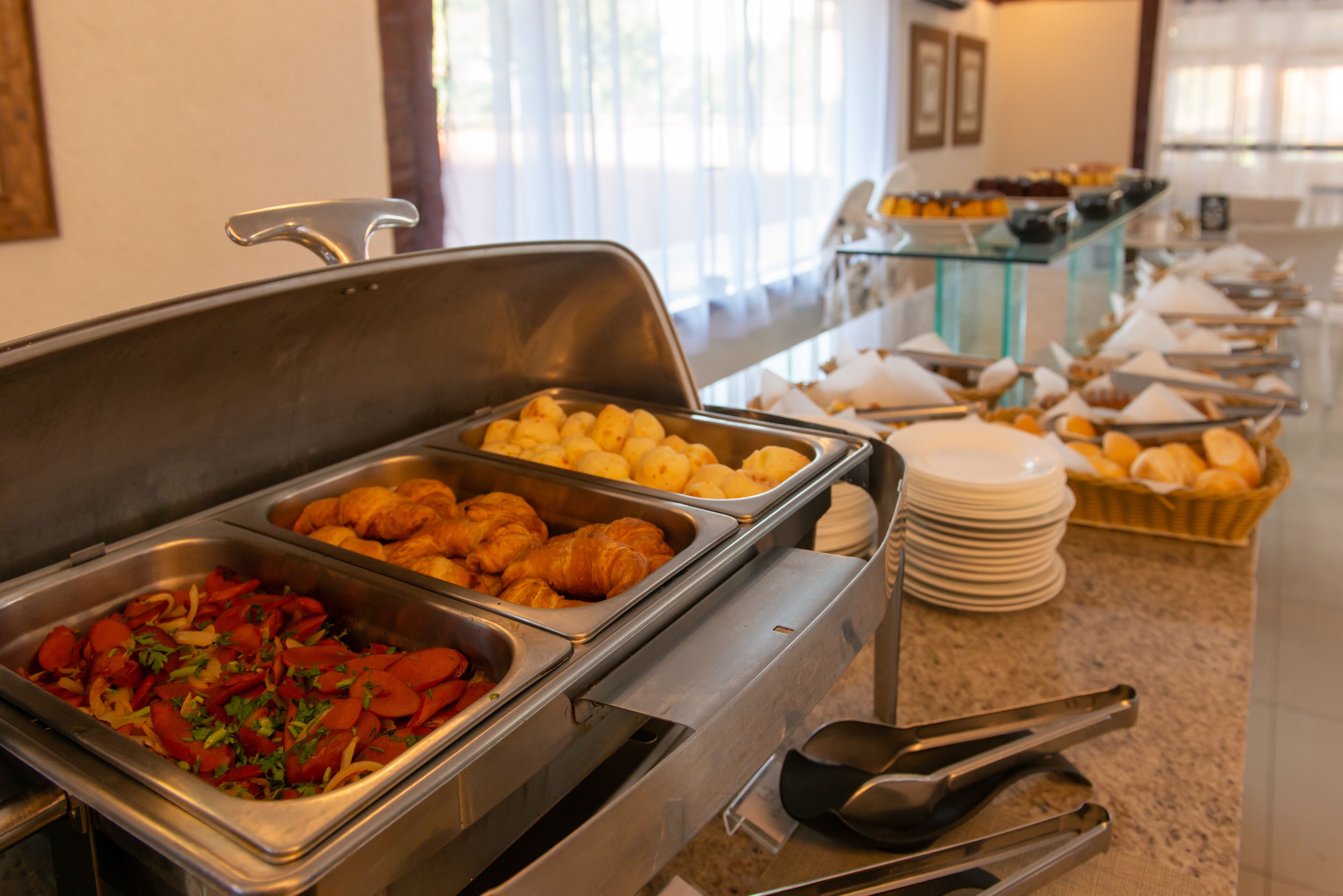 A buffet with various food items including croissants, pastries, and a salad.