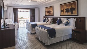Habitación de hotel con dos camas, un escritorio, una silla y vistas al exterior.