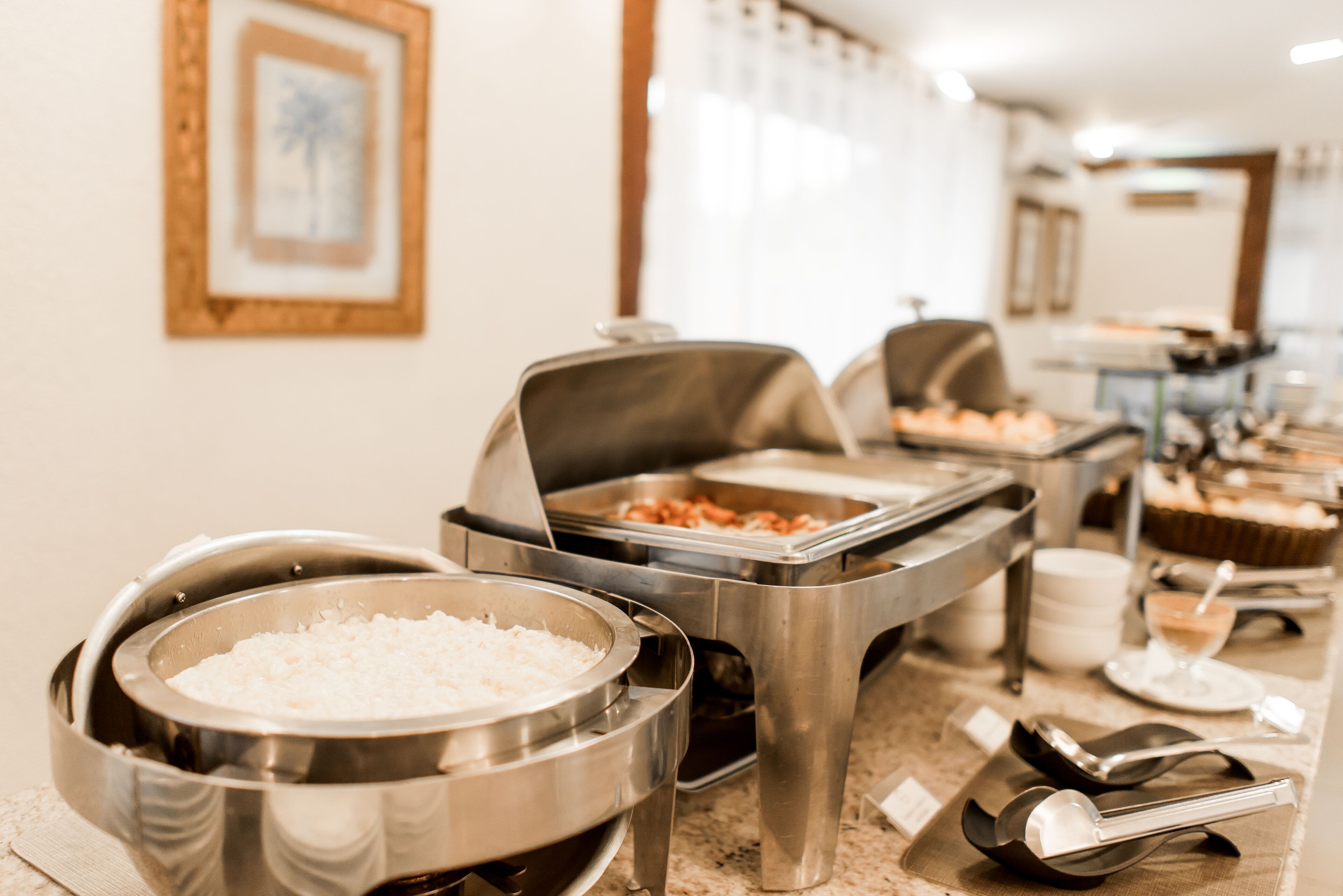 Disposição de buffet com diversos recipientes de comida e utensílios de servir.