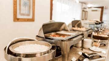 Disposição de buffet com diversos recipientes de comida e utensílios de servir.