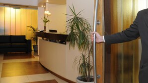 A reception area with a reception desk, a black sofa, and potted plants. - Del Bono Suites Art Hotel (San Juan)