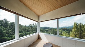 Ein moderner Raum mit großen Fenstern und Blick auf eine bewaldete Landschaft.