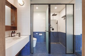 A modern bathroom with a glass-enclosed shower, white tiles, and a blue-tiled floor.