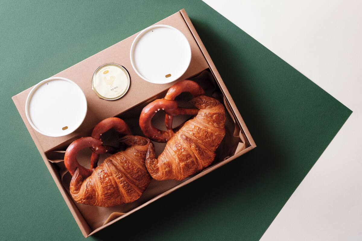 Una caja con cruasanes y dos pequeños recipientes de crema.