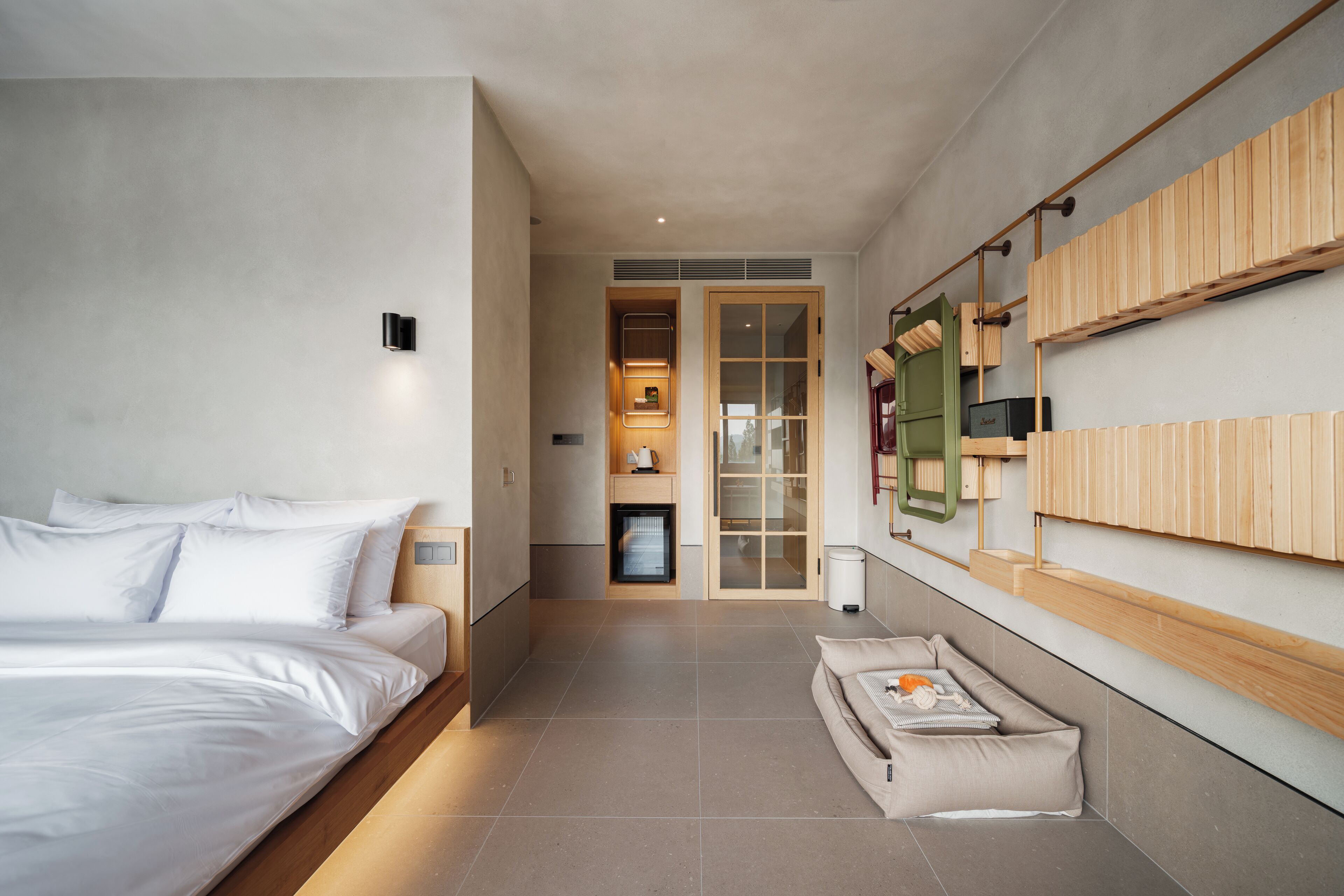 Une chambre d’hôtel moderne dotée d’un grand lit, d’un petit coin salon, d’un téléviseur intégré et d’un meuble mural en bois.