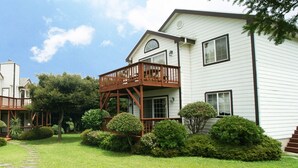 Two white houses with wooden balconies and a stone pathway. - Aewol ParkHill Village (Jeju City)