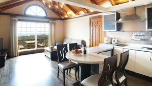 A modern kitchen with a dining area, large windows, and a view of the outdoors. - Aewol ParkHill Village (Jeju City)