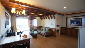 A spacious living area with a wooden ceiling, a sofa, a dining table with chairs, and a refrigerator. - Aewol ParkHill Village (Jeju City)