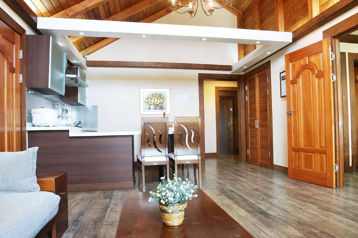 Un interior moderno con techo de madera, una zona de comedor con sillas, un sofá y una cama.