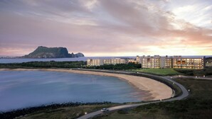 A coastal hotel with a beachfront view, a large building with multiple floors, and a curved road leading to the beach. - Phoenix Island (Seogwipo)
