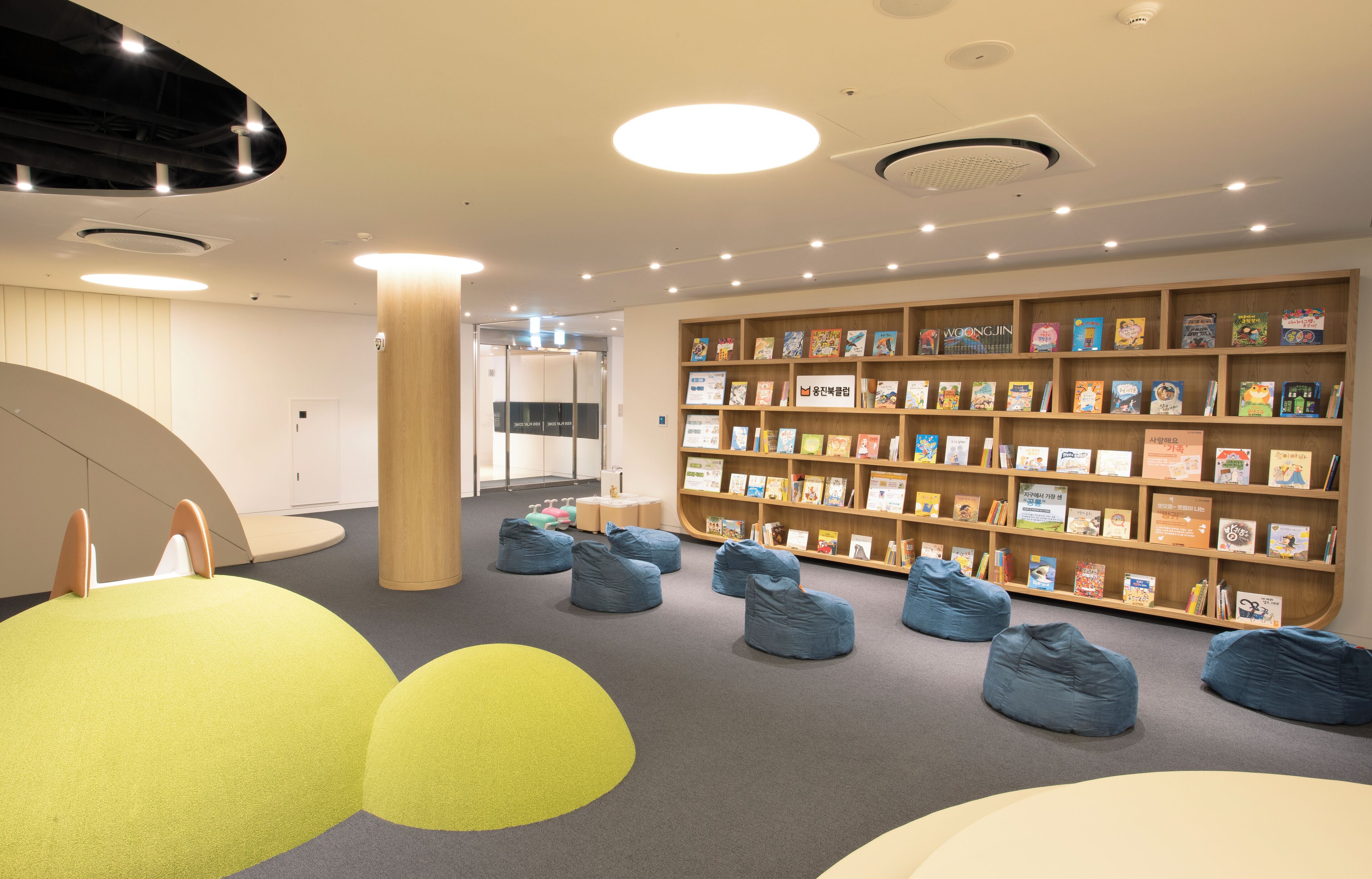 A children's library with bookshelves, bean bags, and a circular seating area.