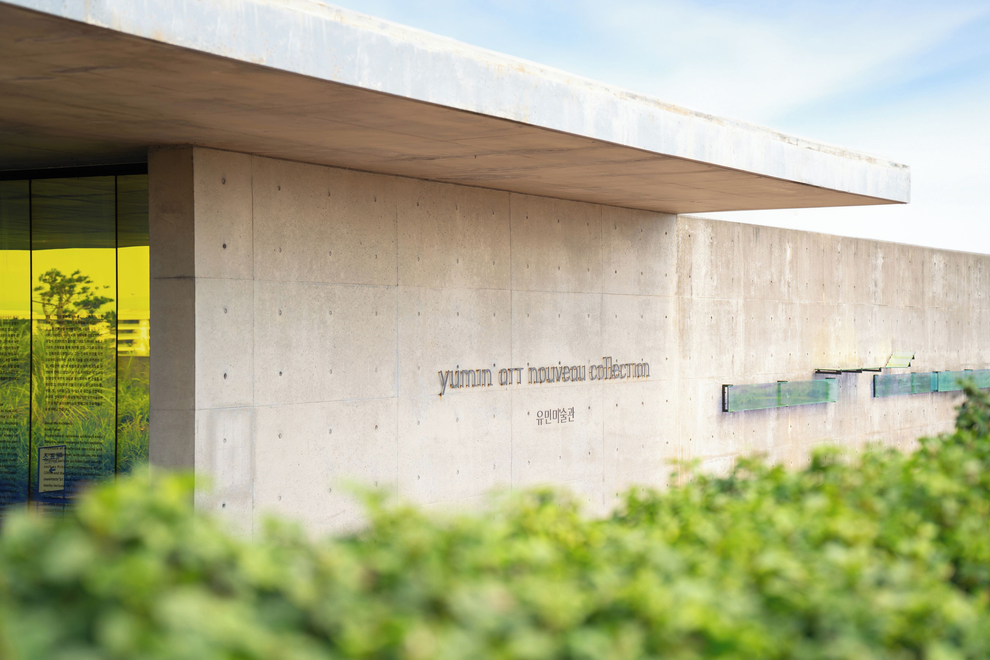 A concrete building facade with a large overhang and a visible inscription.