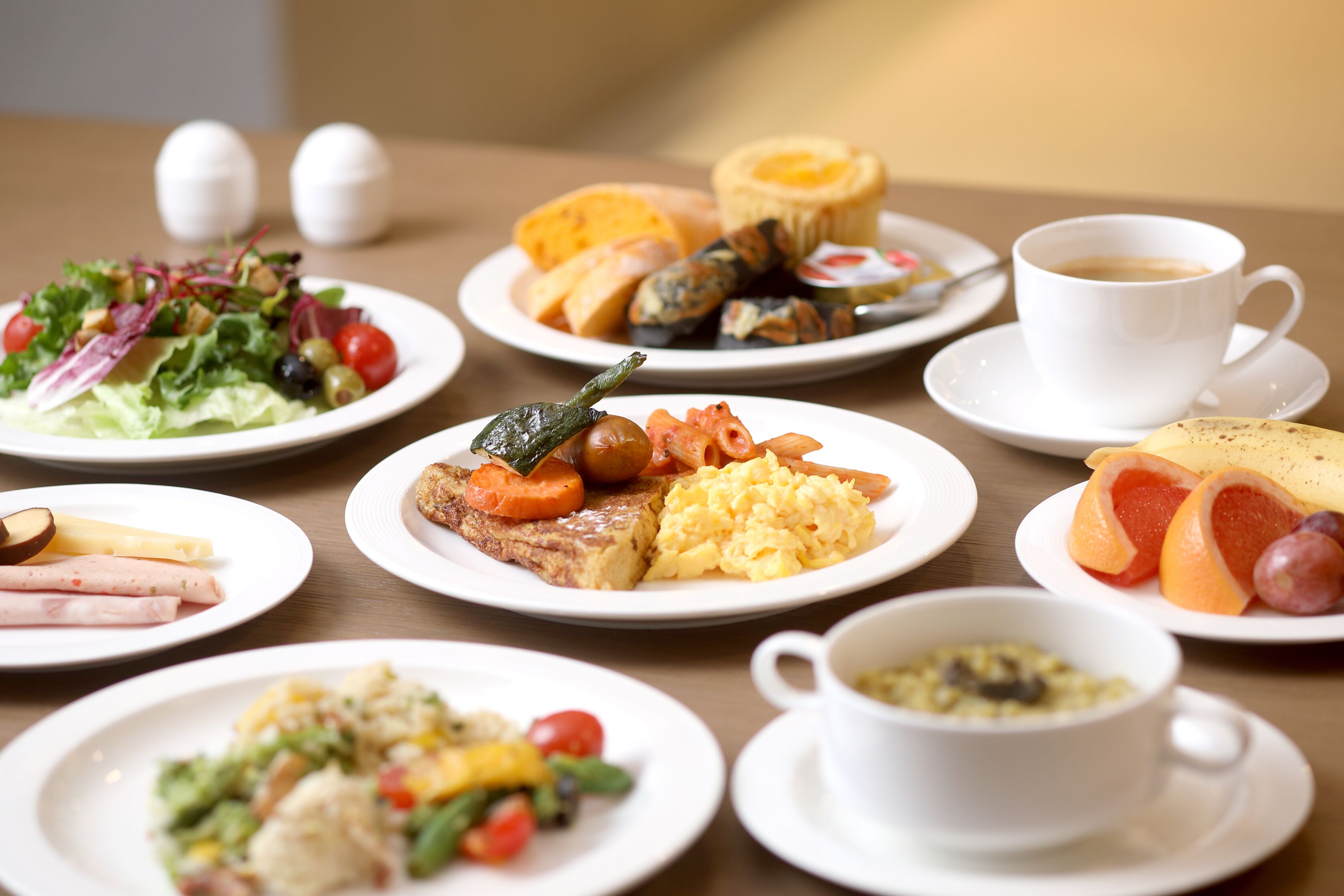 A table with various breakfast dishes including eggs, toast, vegetables, and fruit.