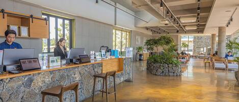 A spacious lobby with a reception desk, bar stools, and seating areas.