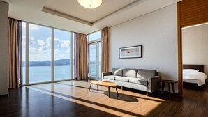 A modern hotel room with a large window, a sofa, a small table, and a bed. - Phoenix Island (Seogwipo)