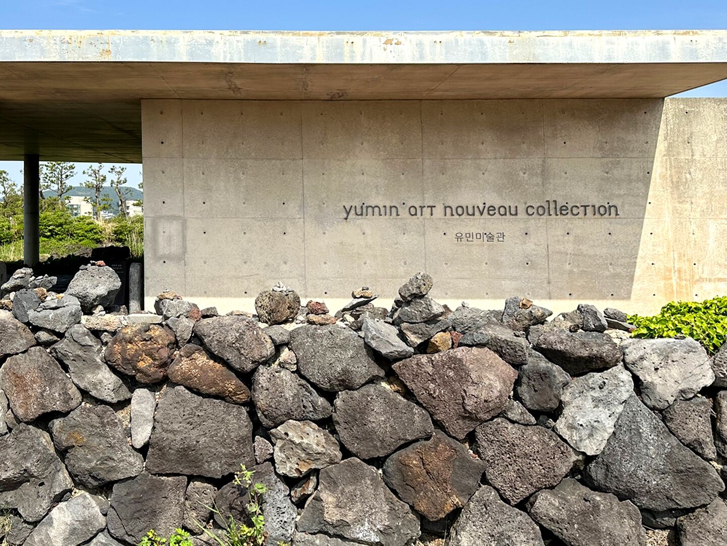 Un muro de piedra con una estructura de concreto encima, que incluye un letrero que dice "yumin art nouveau collection".