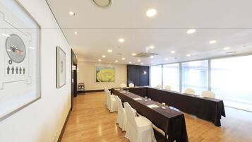A conference room with a long table, white chairs, and framed artwork on the walls.