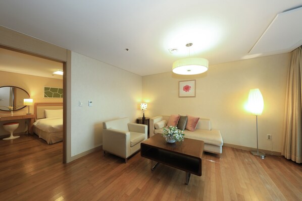 Habitación de hotel con cama, sofá, mesa de centro, lámpara y espejo.