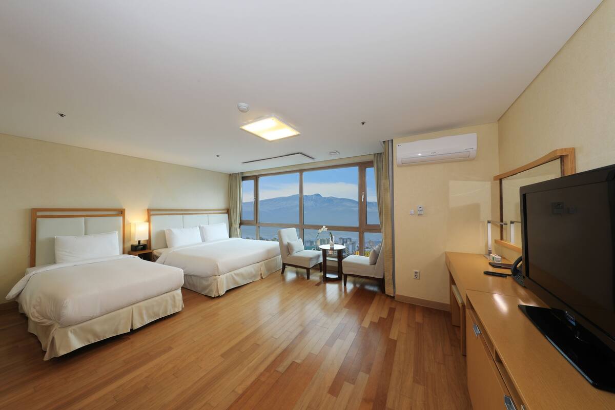Une chambre d’hôtel avec deux lits, une télévision, un bureau et une vue sur les montagnes.