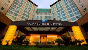 L’entrée de l’hôtel Ocean Suites Jeju présente un design moderne, avec une grande enseigne au-dessus de l’entrée et une allée couverte.