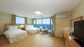 Une chambre d’hôtel avec deux lits, une télévision, un bureau et vue sur la mer.