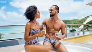 A couple sitting by a hot tub with a scenic view of the ocean and hills. - Aquaria Natal Hotel (Natal)