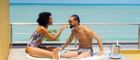 A couple sitting on a sun lounger with a view of the ocean.