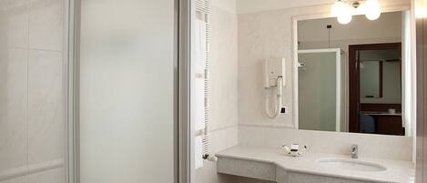 A modern bathroom with a glass shower door, a toilet, a bidet, and a sink with a mirror above it.