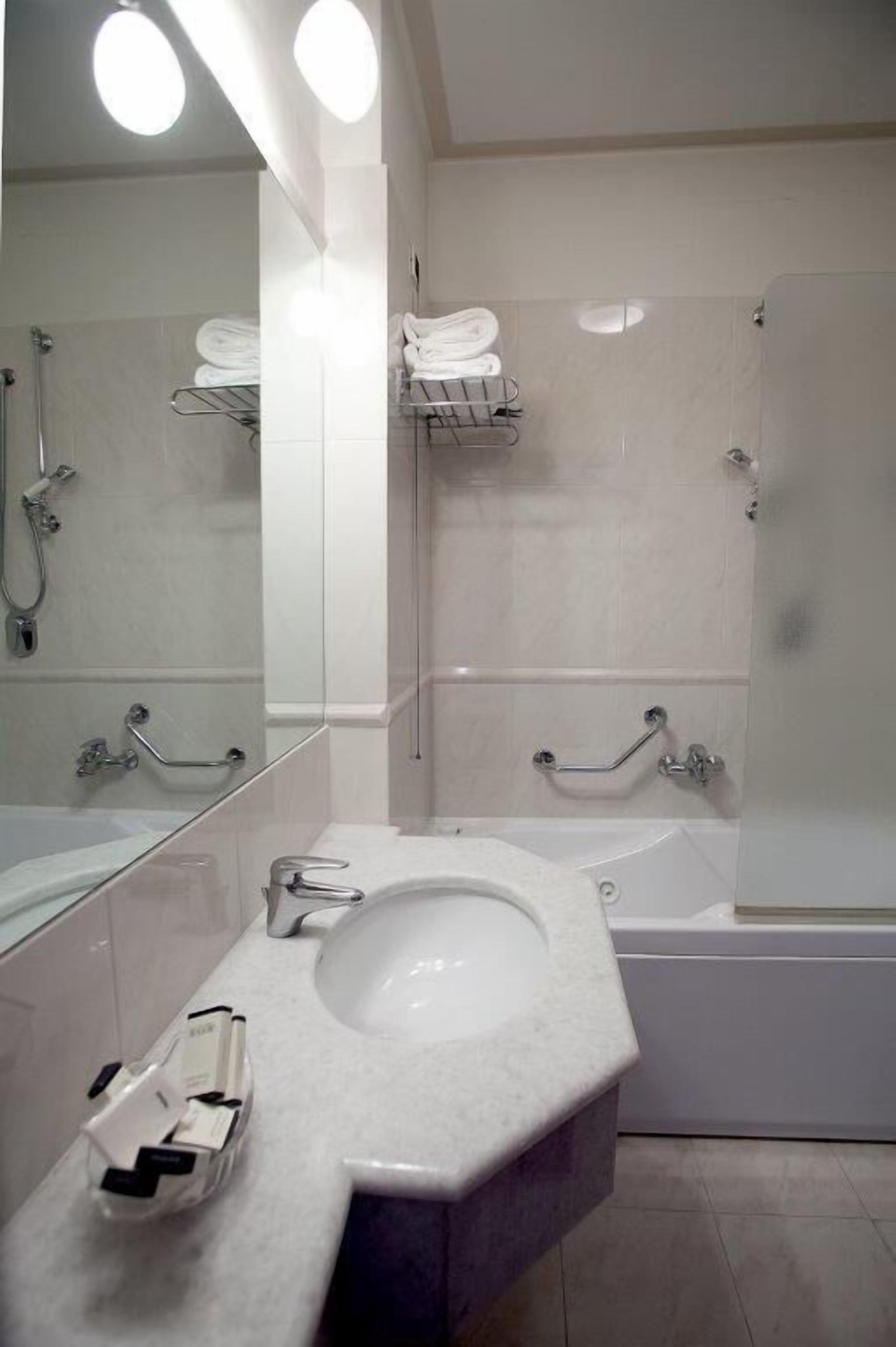 A modern bathroom with a large mirror, white fixtures, a bathtub, and a shower.