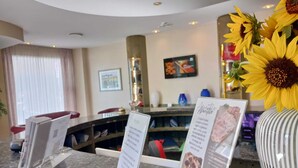 A hotel reception area with a marble counter, a large vase of sunflowers, and a framed picture on the wall. - Palace Hotel (Civitanova Marche)