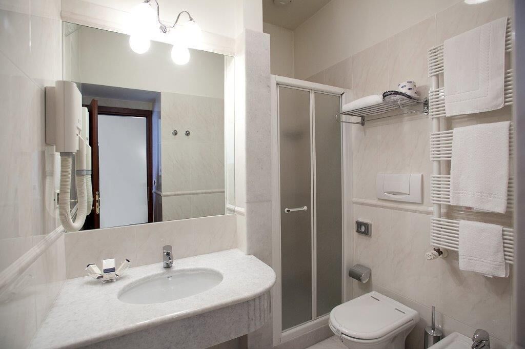 Une salle de bain moderne équipée d’un lavabo, d’un miroir, d’une douche et de toilettes.