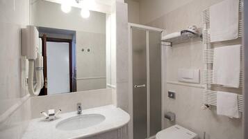 Une salle de bain moderne équipée d’un lavabo, d’un miroir, d’une douche et de toilettes.