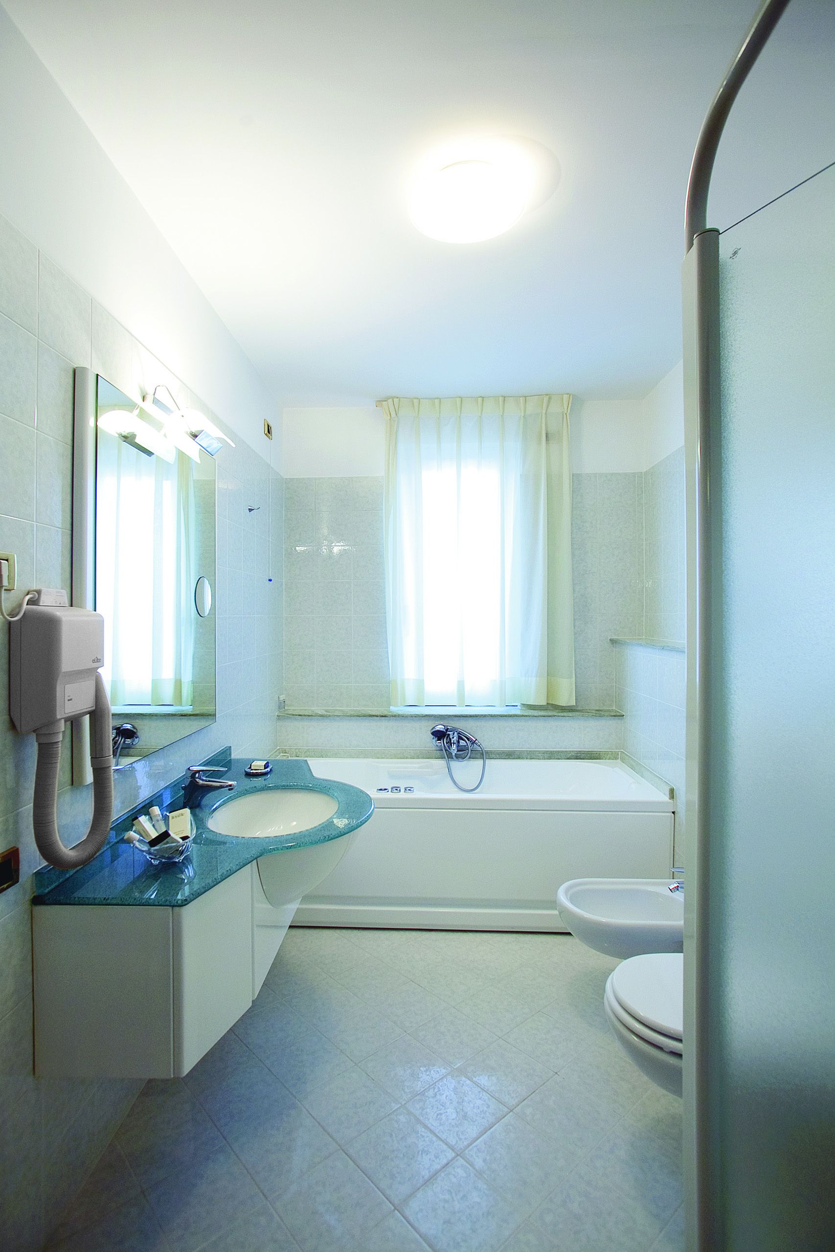 Un baño con lavamanos, espejo y bañera.