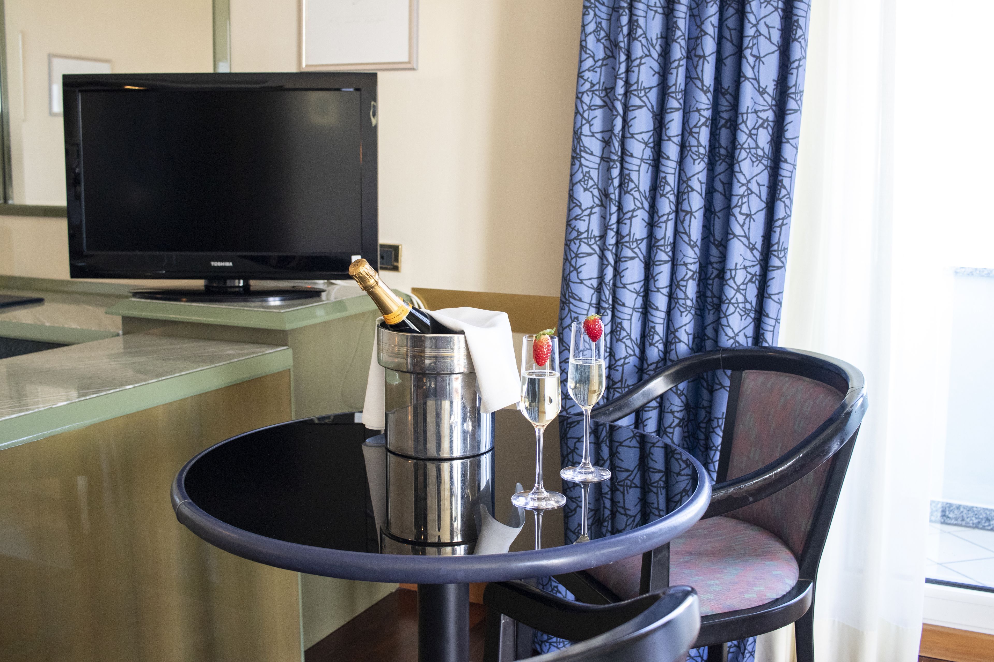 Une chambre d’hôtel équipée d’un mini-bar, d’une télévision, d’un shaker à cocktails et de deux verres décorés d’une fraise.