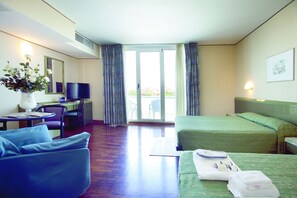 Habitación de hotel con dos camas, un escritorio con silla, televisión y vistas al exterior.