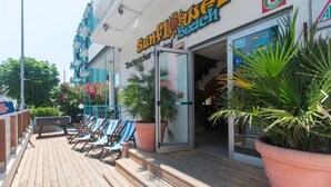 A beachside restaurant with outdoor seating and potted plants.