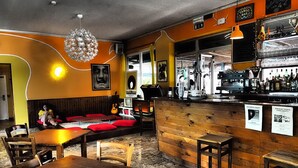 A cozy bar area with wooden furniture, a bar counter, and a hanging light fixture.
