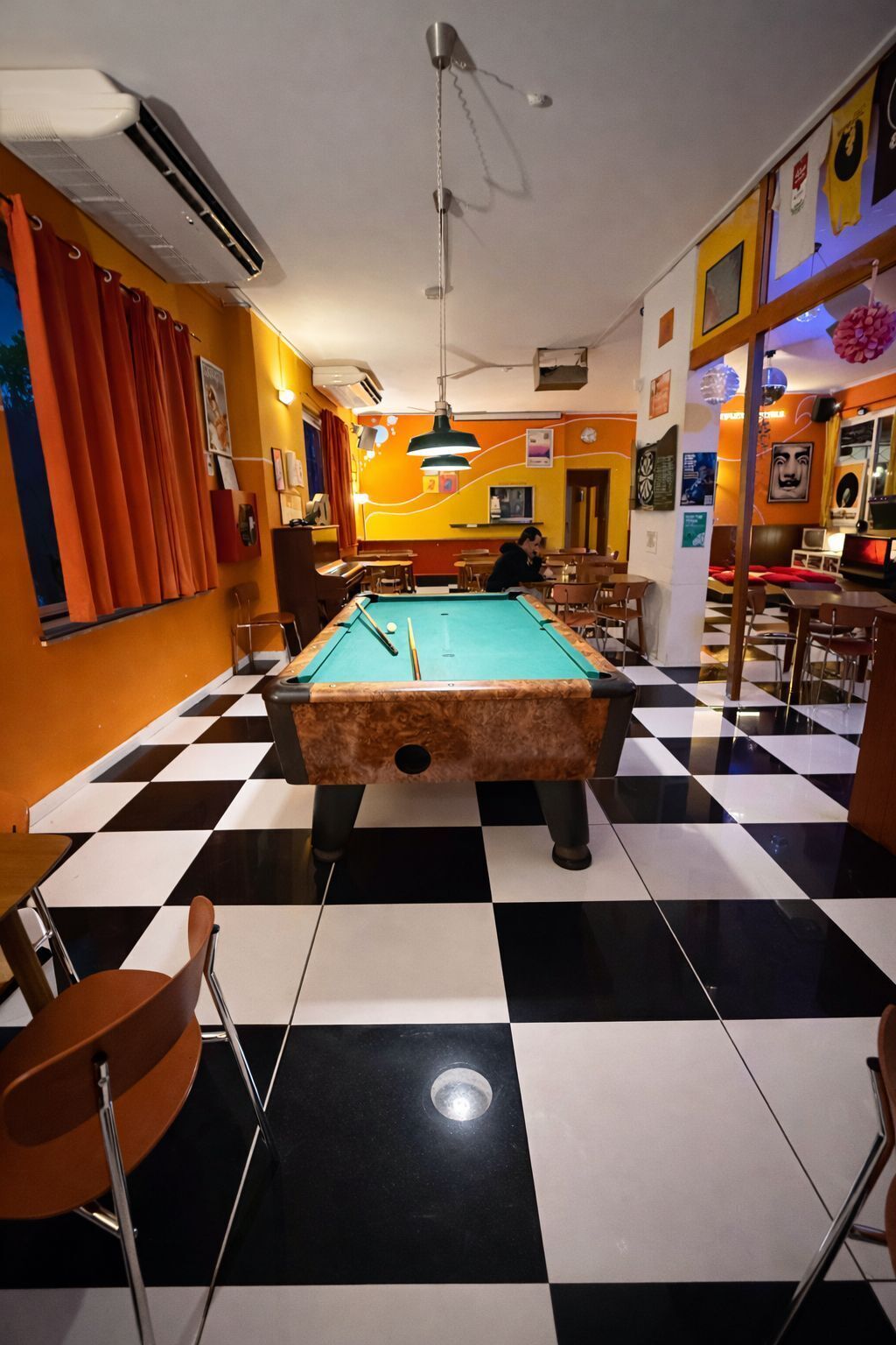 A billiards room with a pool table, checkered floor, and various seating arrangements.
