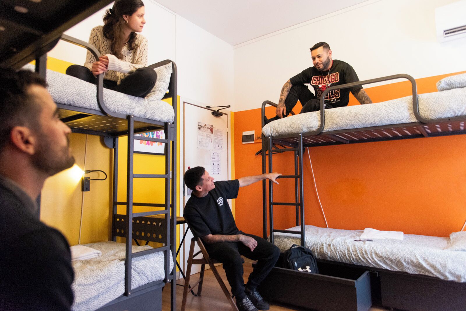 Camas literas en un dormitorio con paredes naranja y una puerta amarilla.