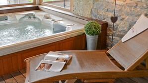 Un espace intérieur chaleureux avec une baignoire en bois, un fauteuil de lecture et une petite plante en pot.