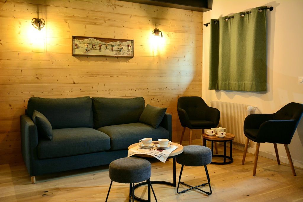 Una stanza accogliente con un divano, due poltrone, un tavolino con tazze e un quadro appeso al muro.