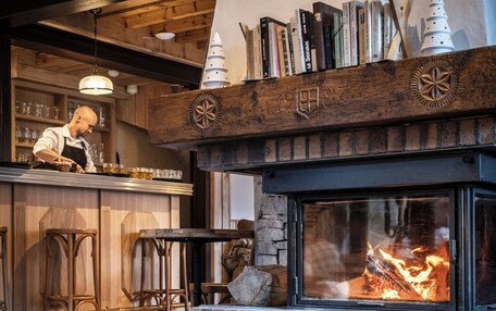 A cozy restaurant interior with a fireplace, wooden bar, and bar stools.