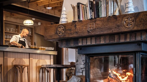 L’intérieur de ce restaurant est chaleureux, avec une cheminée, un bar en bois et des tabourets de bar.