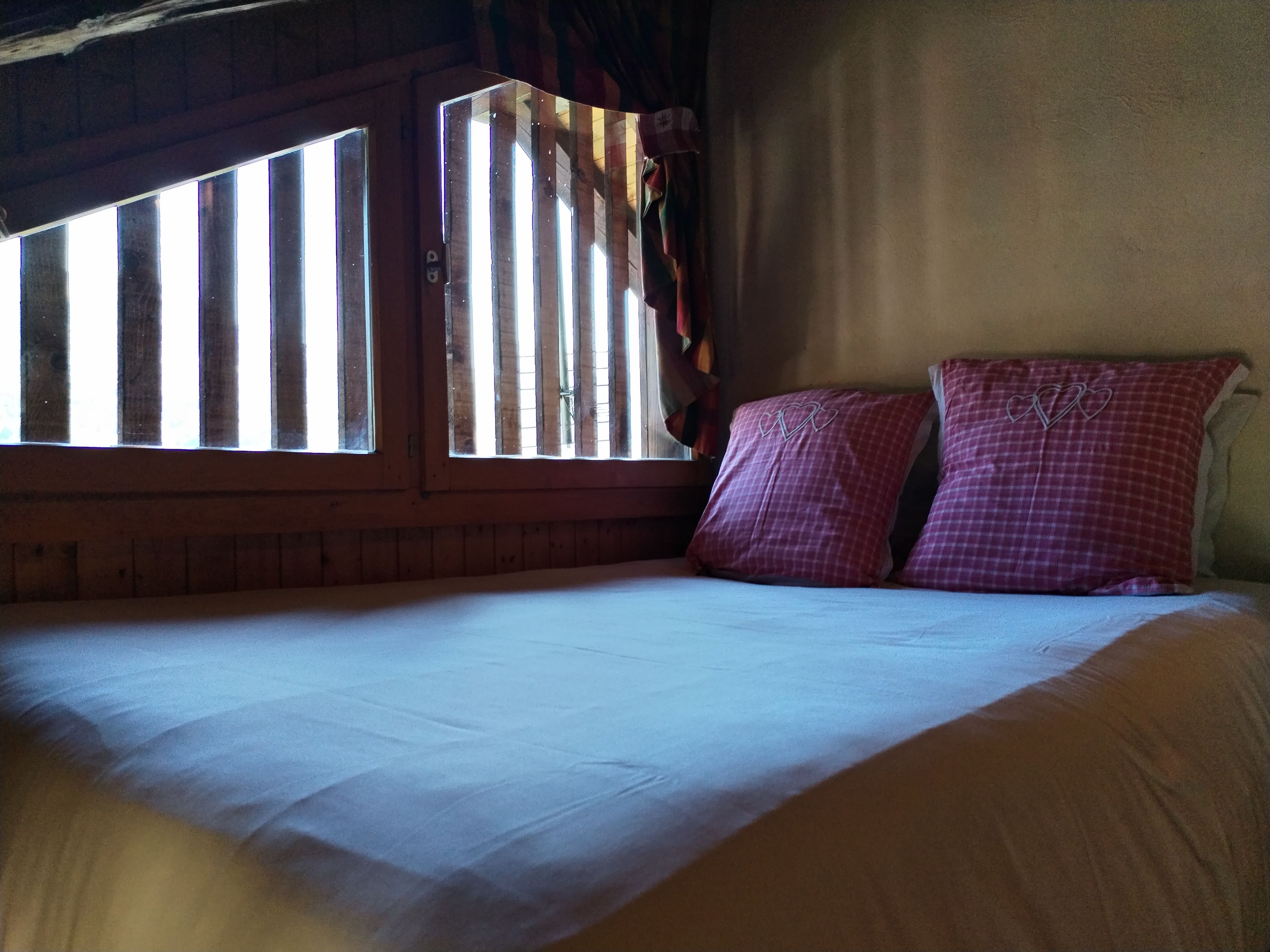A room with a bed, a window with curtains, and a wall with a textured finish.