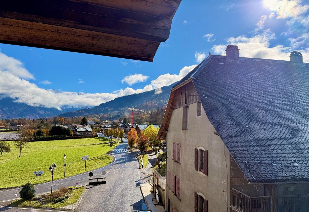 En landlig gade med en bygning til højre, klare himmel og bjerge i baggrunden.