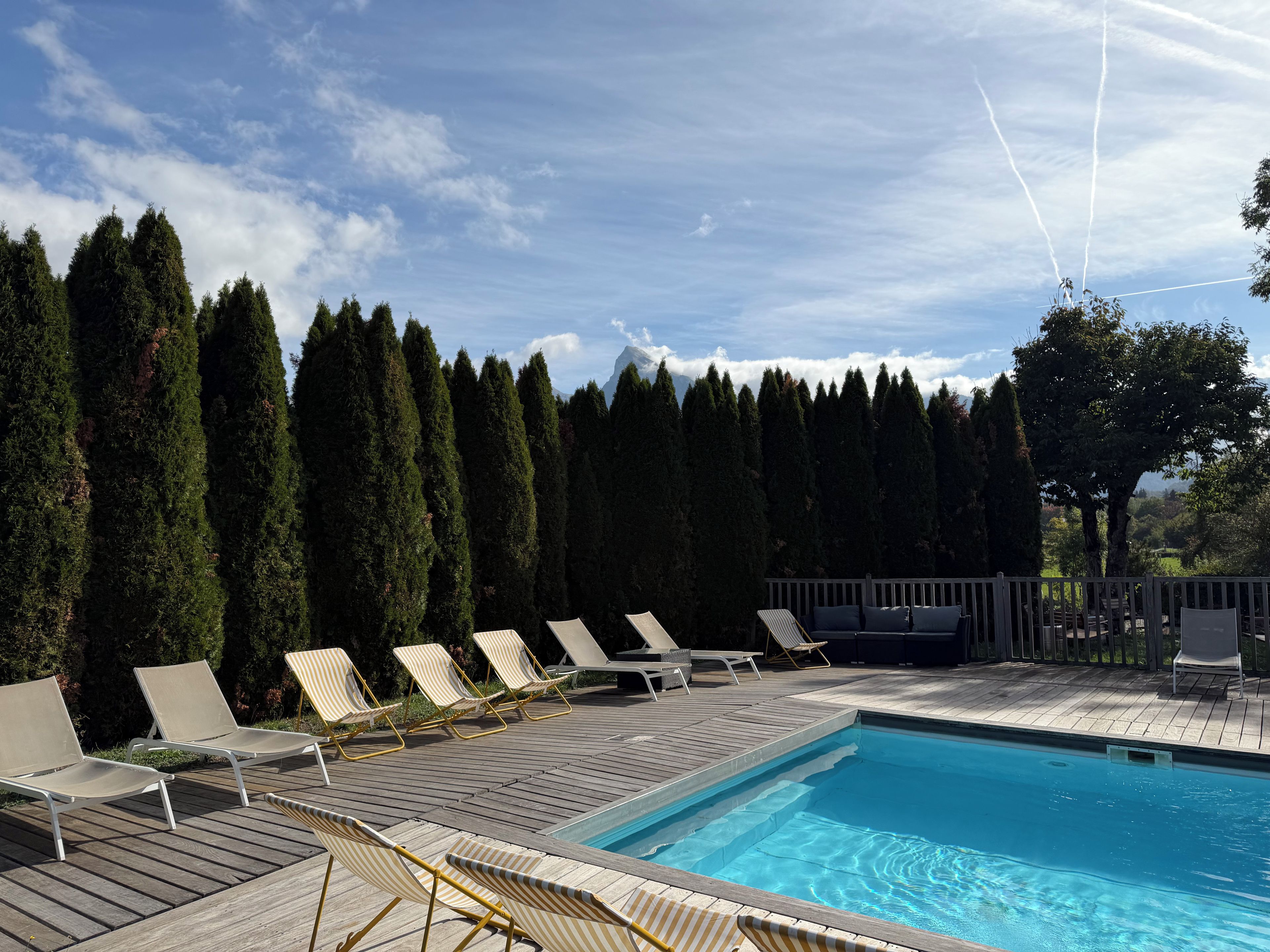 Una piscina con sillones de descanso y una terraza de madera.