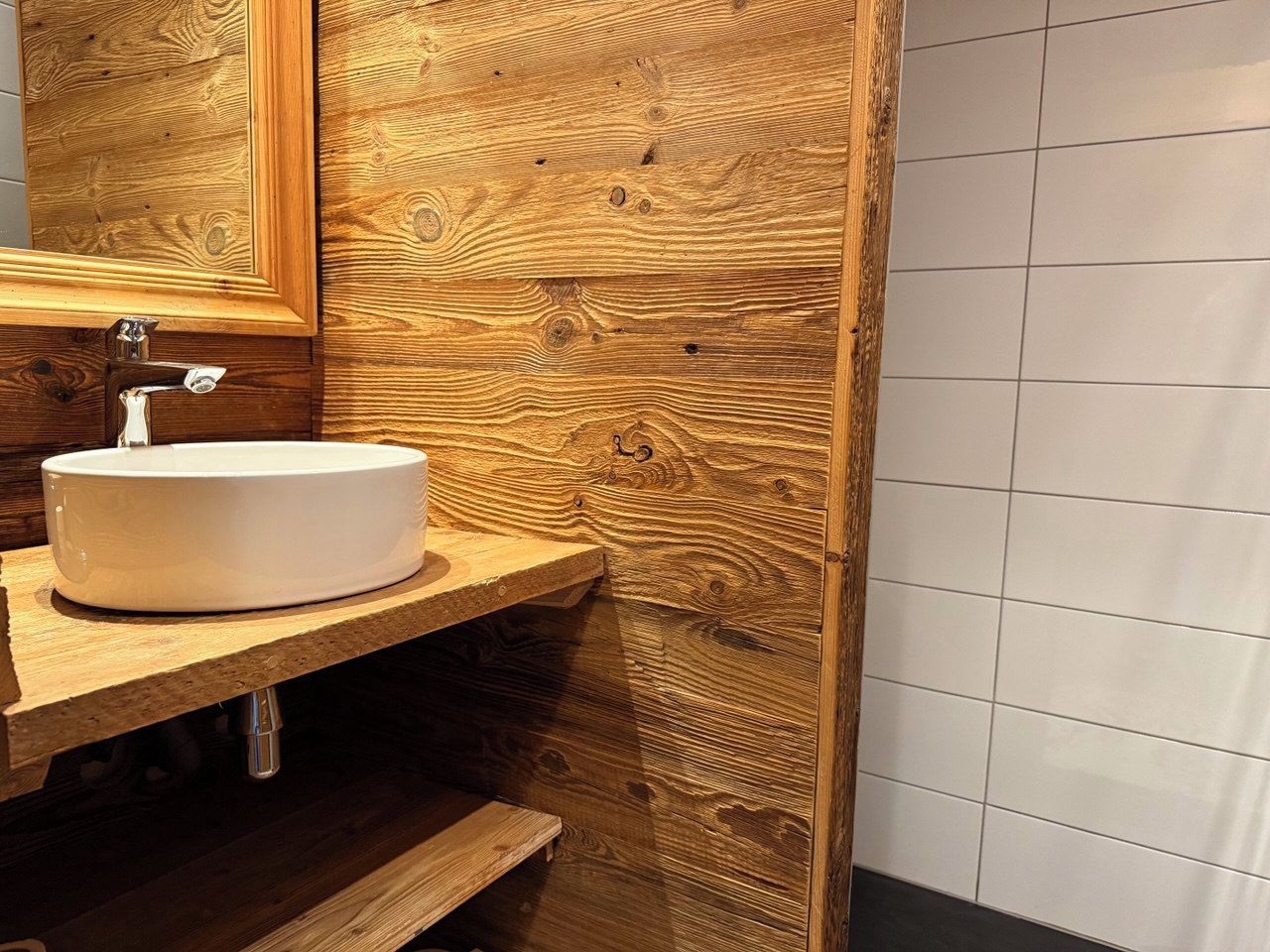 Un baño con tocador de madera, un lavamanos blanco y un espejo.